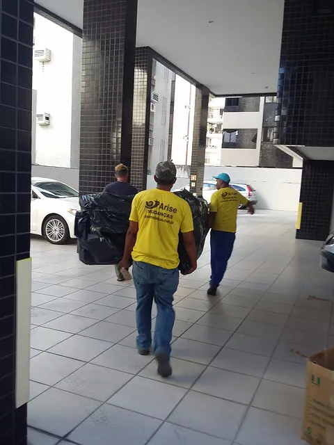 Dois colaboradores da Arise carregando caixas pelo hall de um edifício
