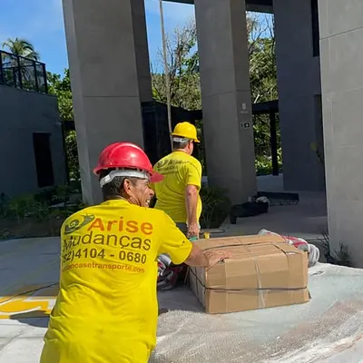 Colaboradores com capacete de segurança embalando volume em obra