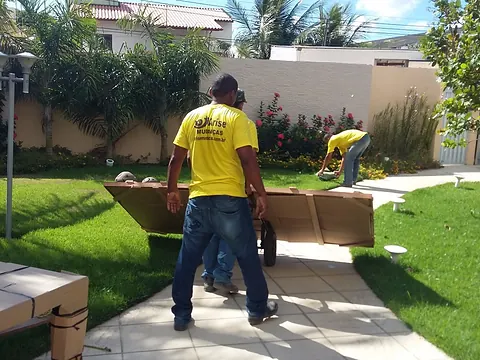 Equipe da Arise carregando móveis embalados no jardim de uma residência